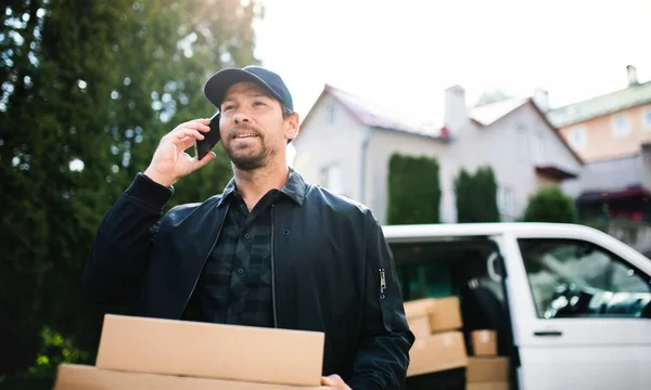 Leverans man kurir leverera paket låda i stan med hjälp av smartphone. — Stockfoto