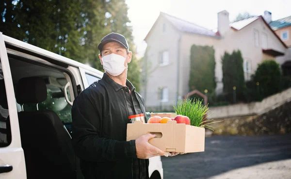 Pošťák kurýr s obličejovou maskou doručující potraviny ve městě. — Stock fotografie