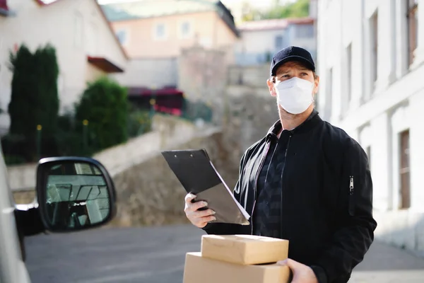 Leverans man kurir med ansikte mask leverera paket låda i stan. — Stockfoto