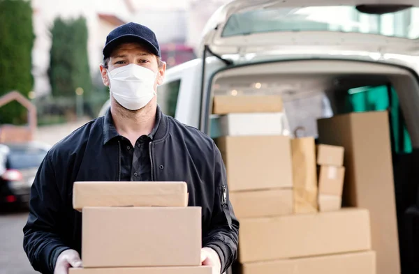 Delivery man courier with face mask delivering parcel boxes in town. — Stock Photo, Image