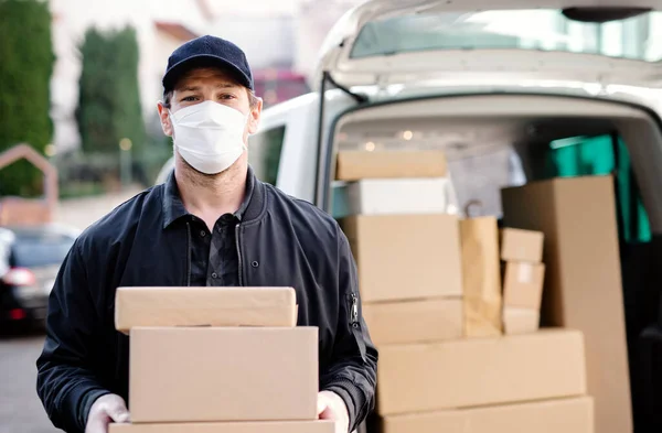 Repartidor mensajero con máscara facial entregando cajas de paquetes en la ciudad . — Foto de Stock