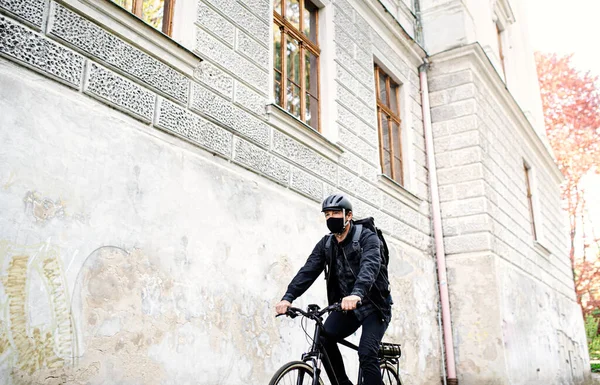 Leverans man kurir med ansiktsmask och cykel cykling i stan. — Stockfoto