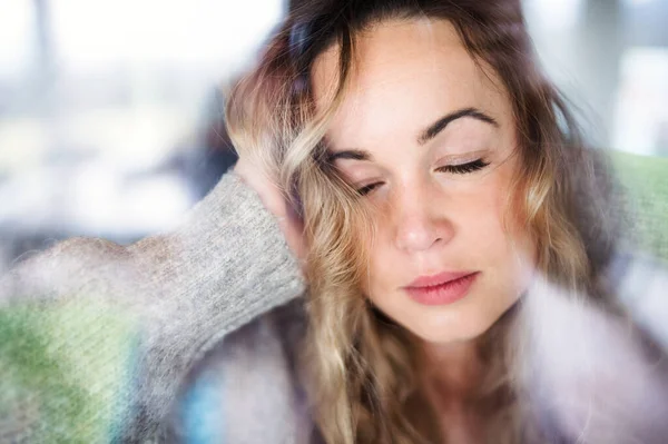 Young sad and depressed woman indoors by window at home. — ストック写真