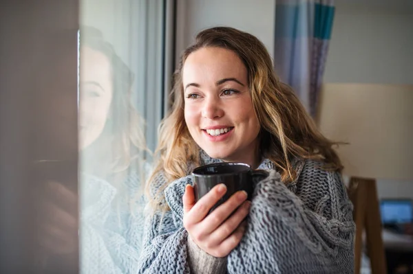 Mujer joven relajándose en el interior de casa con una taza de café o té . —  Fotos de Stock