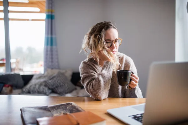 Fiatal nő laptoppal és kávéval otthon dolgozik. — Stock Fotó
