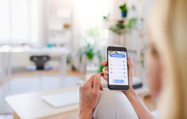 Evde akıllı telefonu olan tanınmayan bir kadın yemek sipariş ediyor..