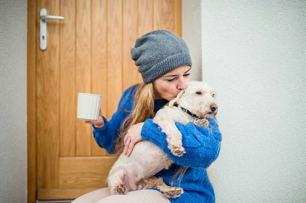 Mujer madura relajándose al aire libre por la puerta principal en casa con café y perro mascota . —  Fotos de Stock