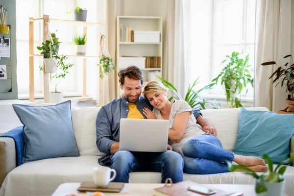 Glada par förälskade sitter hemma, med laptop. — Stockfoto