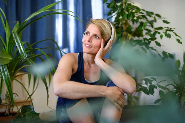 Vista frontal de mujer joven con auriculares en el interior de casa, descansando . — Foto de Stock