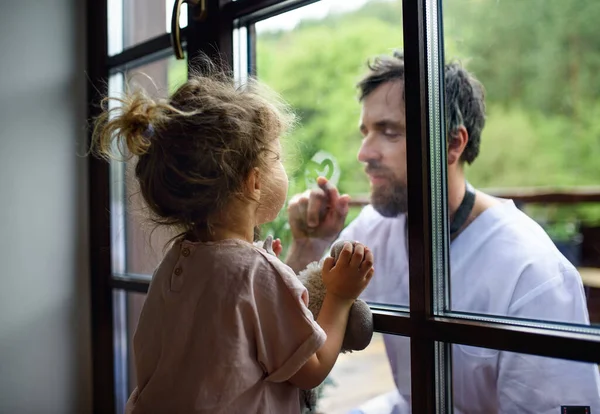 Doctor coming to see family in isolation, window glass separating them. — Stock Photo, Image