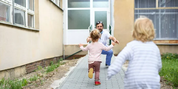 病院の前で父の医者を迎えるために走っている子供たち、コロナウイルスの終わり. — ストック写真