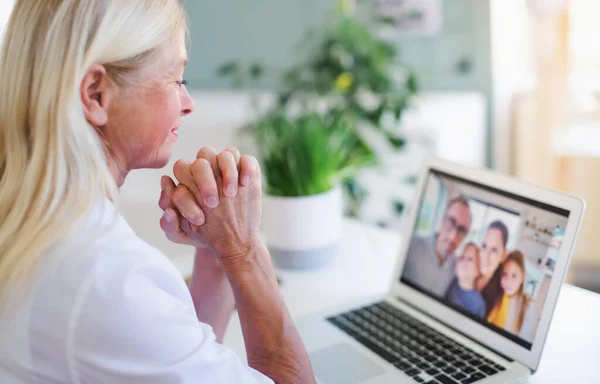 Старша жінка з ноутбуком вдома, концепція сімейного відеодзвінка . — стокове фото