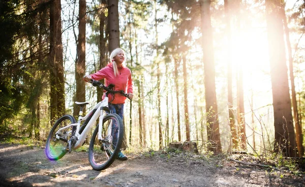 Donna anziana attiva con e-bike ciclismo all'aria aperta nella natura . — Foto Stock