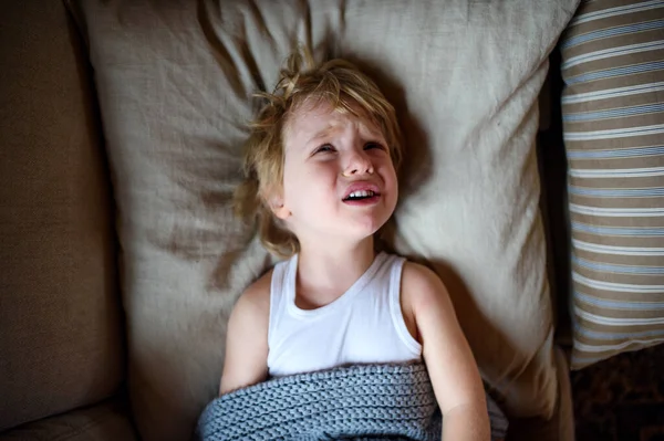 Vue du dessus de pleurer petit garçon malade au lit à l'intérieur à la maison . — Photo