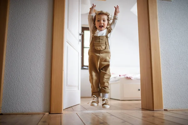 Små småbarn flicka hoppar inomhus hemma, har kul. — Stockfoto