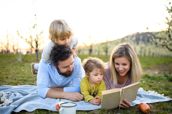 Familie en kleine kinderen met camera en boek buiten in de lente natuur, rusten. — Stockfoto