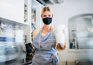 Kafe sahibi kadın yüz maskesi ile çalışıyor, karantinadan sonra açık..
