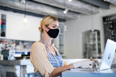 Coffee shop woman owner working with face mask, open after lockdown quarantine. clipart