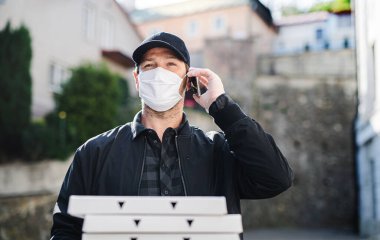 Akıllı telefon ve yüz maskeli kurye kasabaya pizza getiriyor..