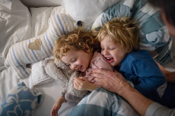 Zwei kleine lachende Kinder mit unkenntlich gemachtem Vater zu Hause, die Spaß haben. — Stockfoto