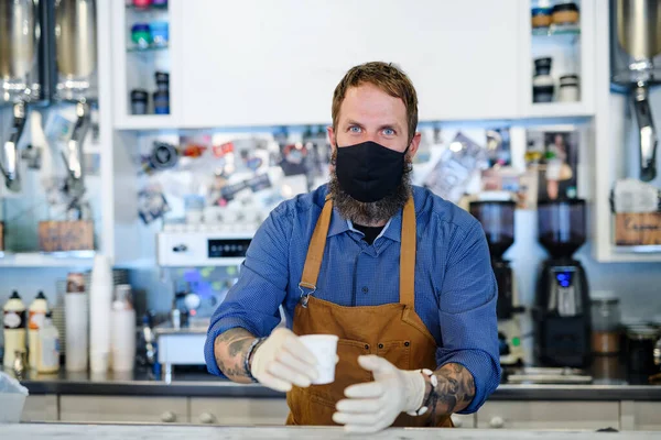 Barista con maschera viso in caffetteria, isolamento, quarantena, coronavirus, torna al concetto normale. — Foto Stock