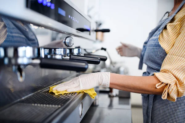 Propietaria de cafetería que trabaja con guantes, máquina desinfectante . — Foto de Stock