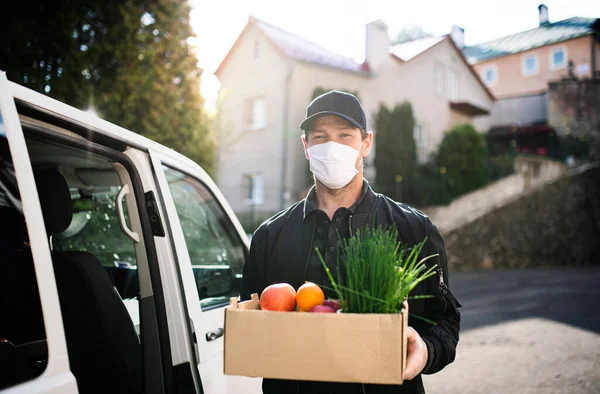 Bezorger koerier met gezichtsmasker levert boodschappen in de stad. — Stockfoto