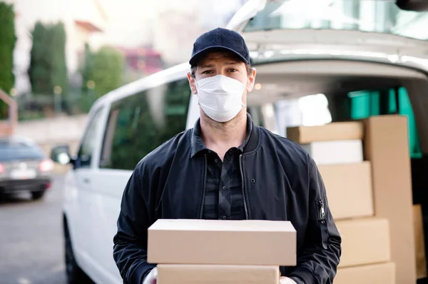 Repartidor mensajero con máscara facial entregando cajas de paquetes en la ciudad . — Foto de Stock