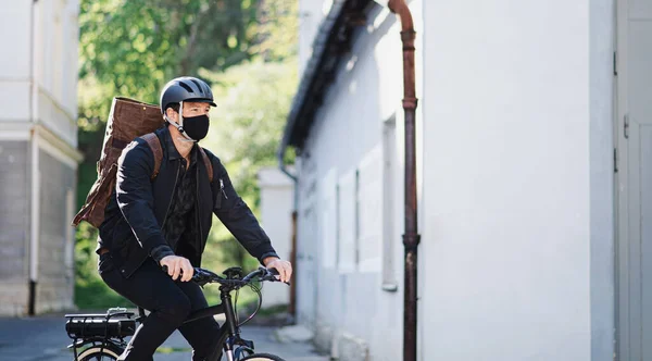 Курьер с маской для лица и велосипедным велосипедом в городе . — стоковое фото