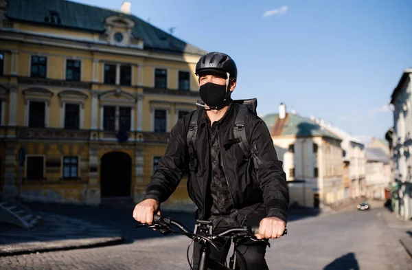 Entrega mensajero hombre con máscara facial y ciclismo en bicicleta en la ciudad . —  Fotos de Stock