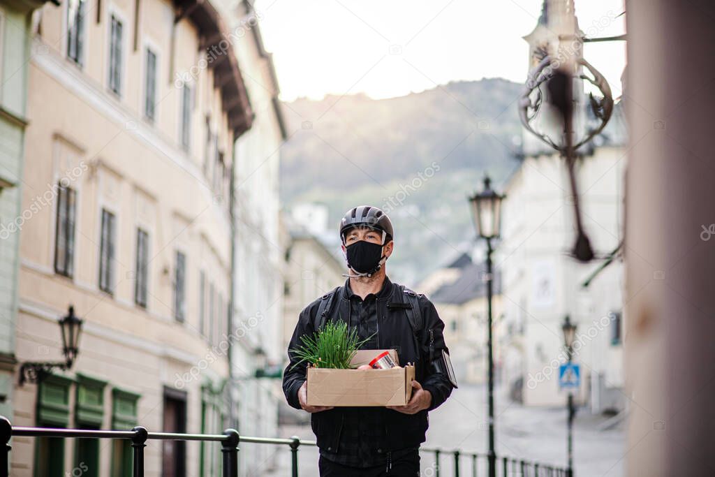 Delivery man courier with face mask delivering groceries in town.