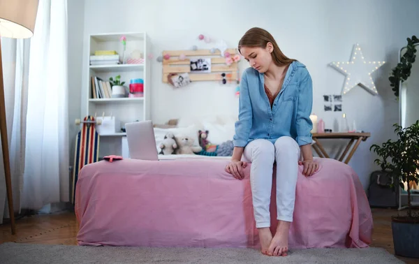 Sorglig och orolig ung flicka med bärbar dator sitter inomhus, internet missbruk koncept. — Stockfoto