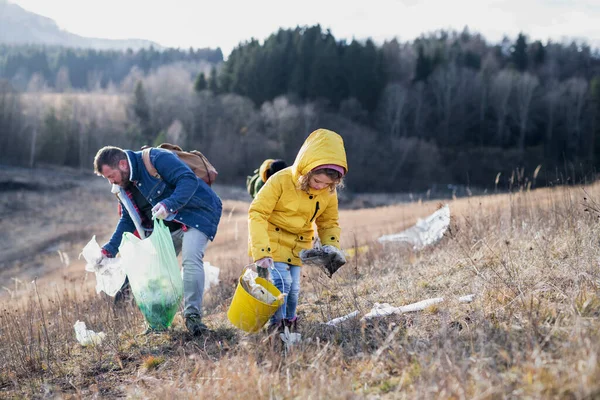 Malé dítě s aktivisty sbírat odpadky v přírodě, koncepce znečištění životního prostředí. — Stock fotografie
