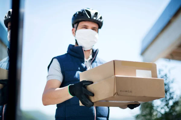 Kurir med ansiktsmask som levererar paket, koronavirus och karantänkoncept. — Stockfoto