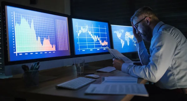 Empresário frustrado com computador sentado à secretária, a trabalhar até tarde. Conceito de crise financeira . — Fotografia de Stock