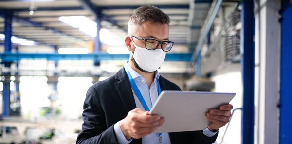 Técnico o ingeniero con máscara protectora y tableta trabajando en fábrica industrial . — Foto de Stock