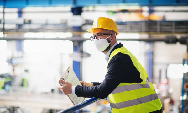 Técnico o ingeniero con máscara protectora y casco de pie en fábrica industrial . —  Fotos de Stock