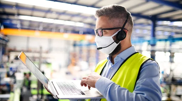 Τεχνικός ή μηχανικός με προστατευτική μάσκα και laptop που εργάζεται σε βιομηχανικό εργοστάσιο. — Φωτογραφία Αρχείου