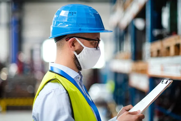 Technik nebo inženýr s ochrannou maskou a helmou pracující v průmyslové továrně. — Stock fotografie