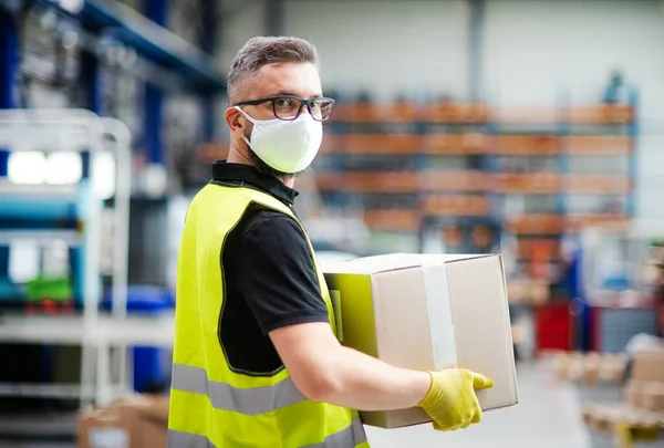 Hombre trabajador con máscara protectora que trabaja en fábrica industrial o almacén . — Foto de Stock