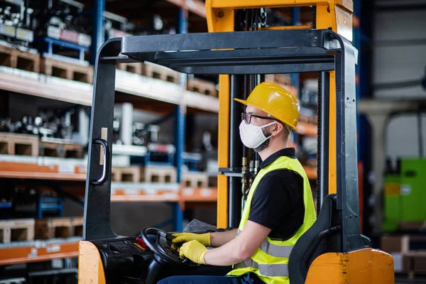 Conductor de carretilla elevadora de hombre trabajador con máscara protectora que trabaja en fábrica o almacén industrial . — Foto de Stock