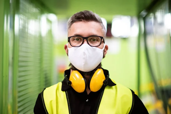 Homem trabalhador com máscara protetora em pé na fábrica industrial ou armazém . — Fotografia de Stock