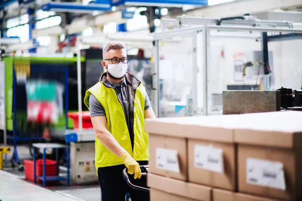 Hombre trabajador con máscara protectora que trabaja en fábrica industrial o almacén . — Foto de Stock