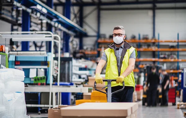 Werknemer met beschermend masker werkzaam in industriële fabriek of magazijn. — Stockfoto