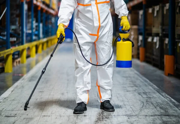 Travailleur homme avec masque de protection et costume désinfectant usine industrielle avec pistolet pulvérisateur . — Photo