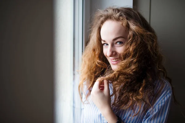 Close-up portrait of young woman standing by window indoors at home. — Stock Photo, Image