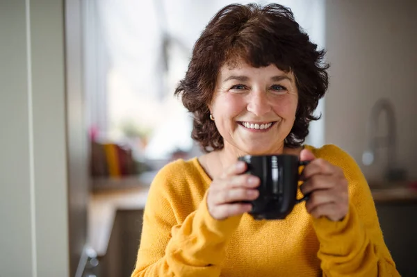 Oudere vrouw met kopje koffie thuis, ontspannen. — Stockfoto