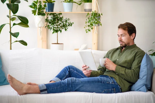 Homme assis sur le canapé et le livre de lecture à la maison, concept de verrouillage . — Photo