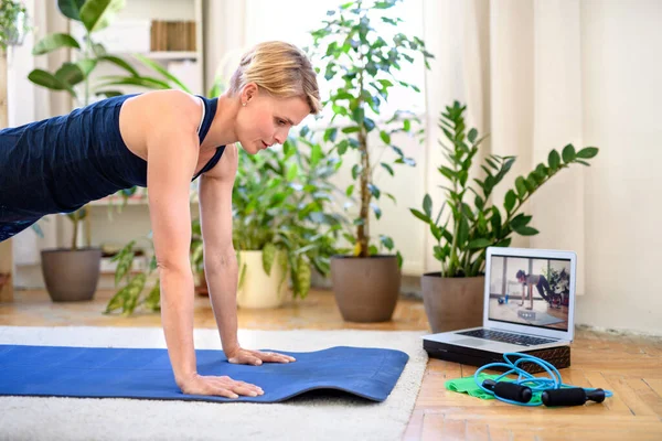 Mulher em casa fazendo exercícios de fitness em casa, assistindo vídeo tutorial online . — Fotografia de Stock