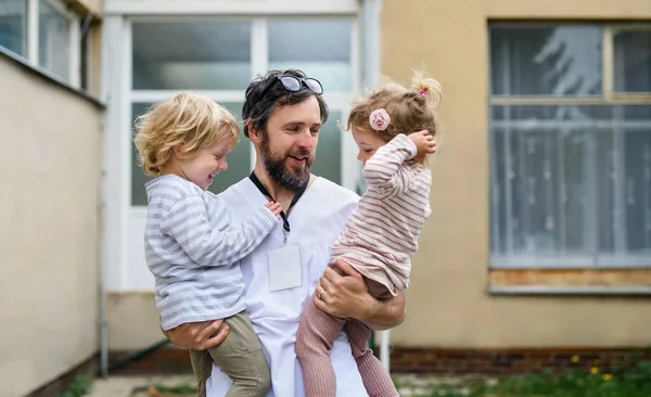 Děti zdraví otce lékaře před nemocnicí, konec koronaviru. — Stock fotografie